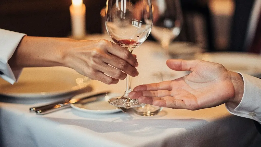 Échange discret et bienveillant entre un serveur et un client dans un restaurant raffiné
